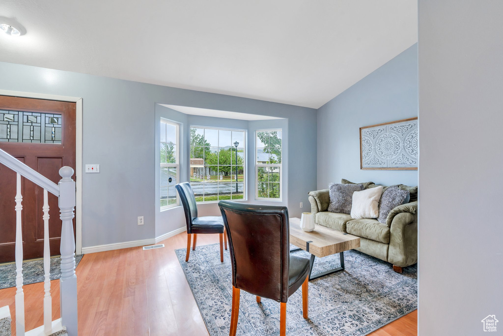 Living room featuring light wood-style floors, baseboards, stairs, and lofted ceiling