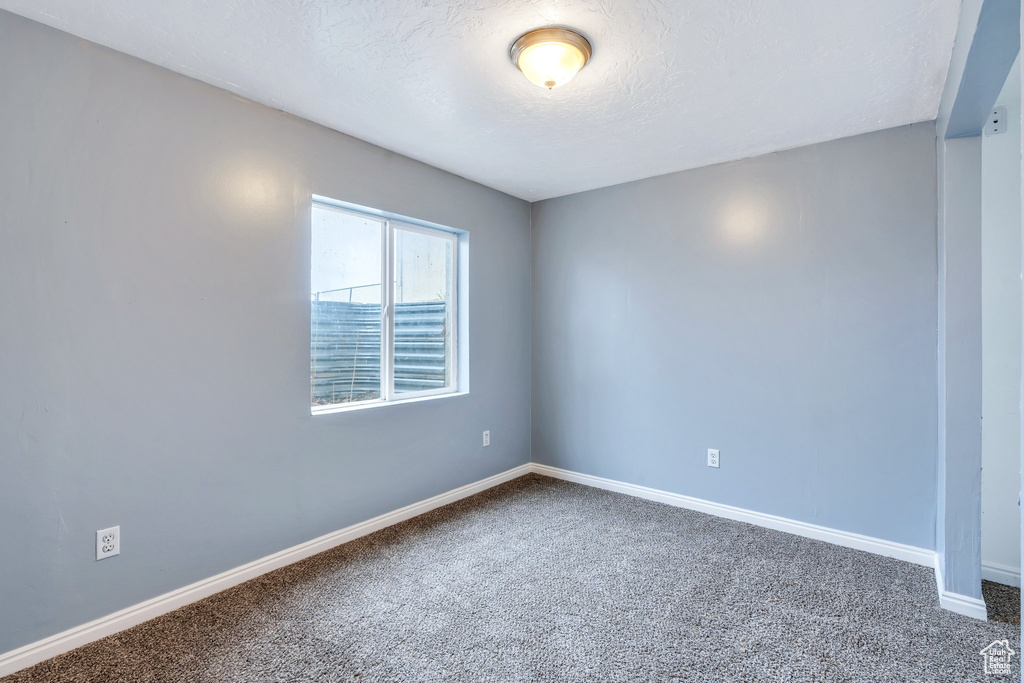 Unfurnished room with carpet floors, baseboards, and a textured ceiling