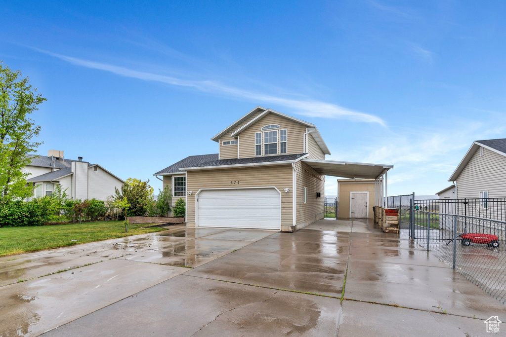 Traditional home with driveway, an attached garage, fence, and a carport