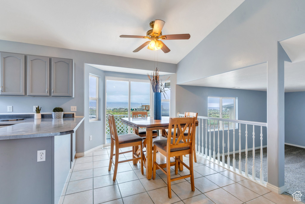 Dining area featuring ceiling fan, baseboards, light tile patterned floors, and lofted ceiling