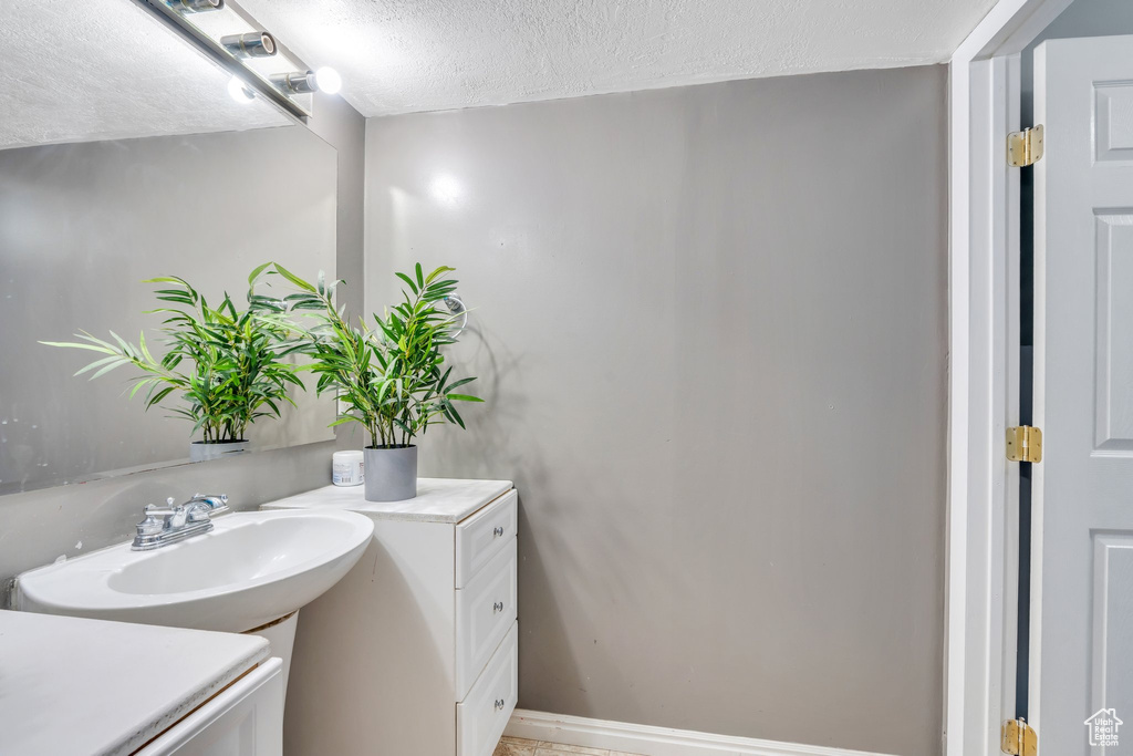 Bathroom featuring a textured ceiling, a sink, and baseboards