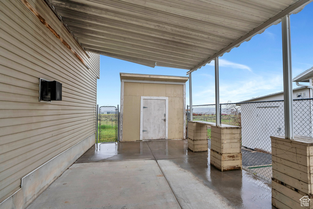 View of patio with a gate, fence, and a shed