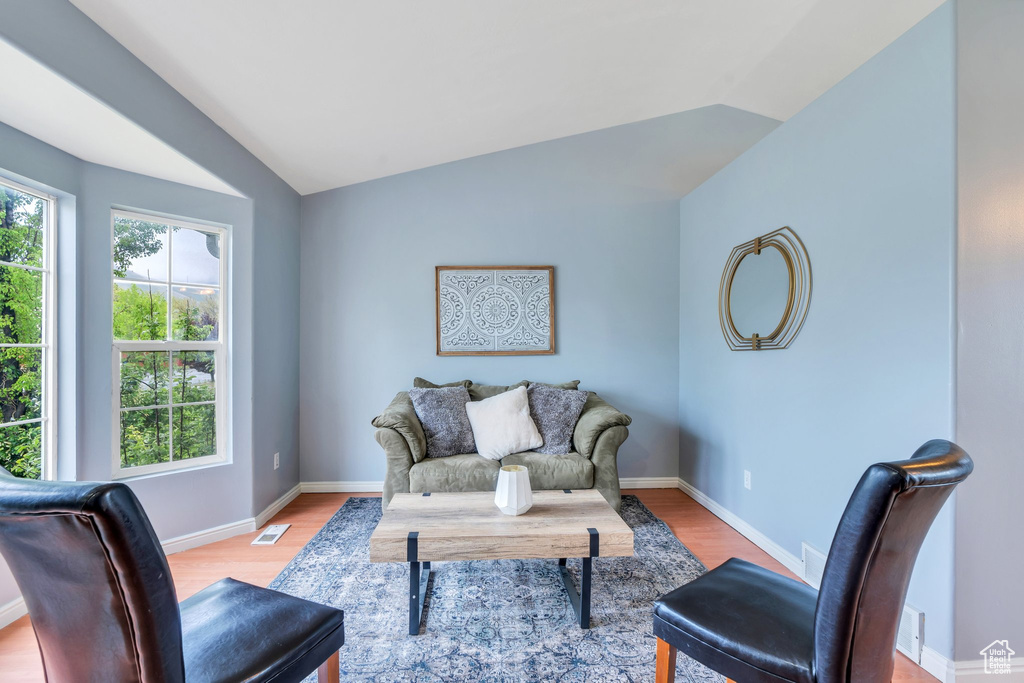 Living area with vaulted ceiling, light wood-style flooring, and baseboards