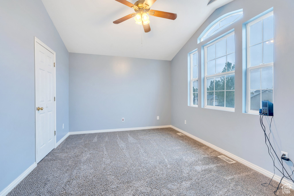 Empty room featuring vaulted ceiling, carpet flooring, ceiling fan, and baseboards