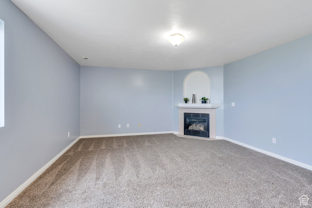 Unfurnished living room with carpet floors, a tile fireplace, and baseboards