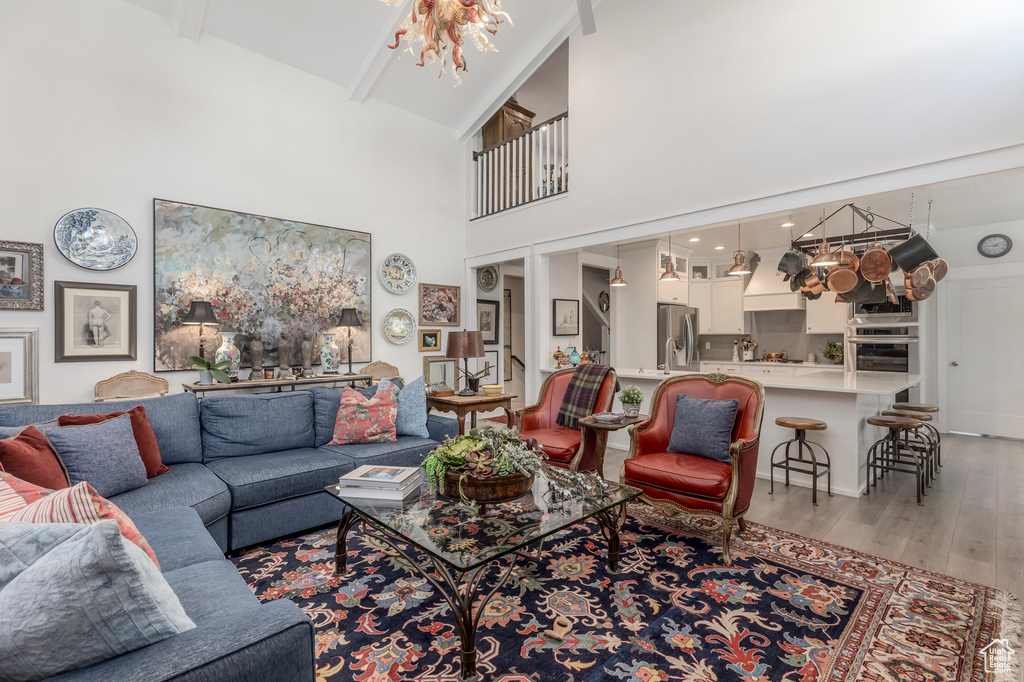 Living area featuring light wood-type flooring, high vaulted ceiling, and beamed ceiling
