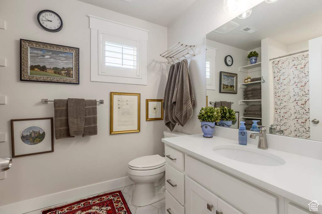 Full bathroom with plenty of natural light, toilet, baseboards, and vanity