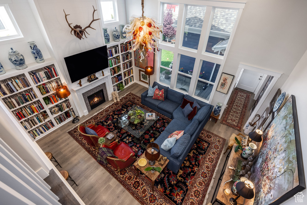 Living room featuring wood finished floors, a towering ceiling, and a fireplace with flush hearth