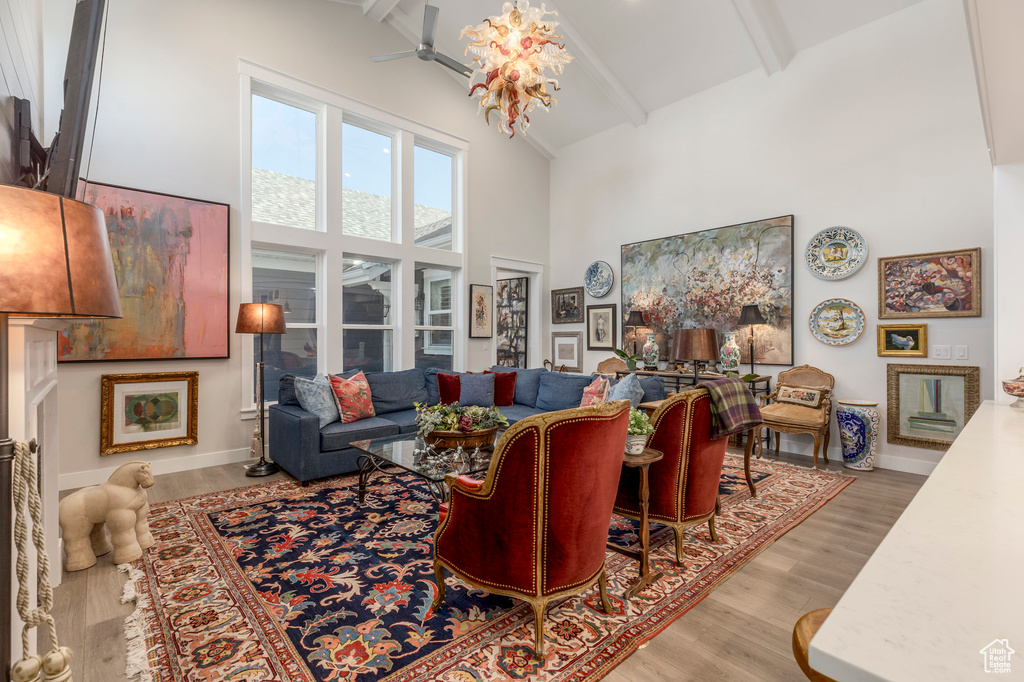 Living room with high vaulted ceiling, beamed ceiling, wood finished floors, ceiling fan, and baseboards