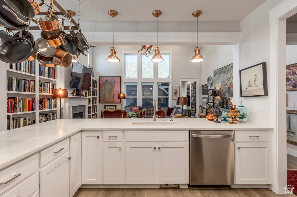 Kitchen with stainless steel dishwasher, a fireplace, light countertops, and light wood-style floors