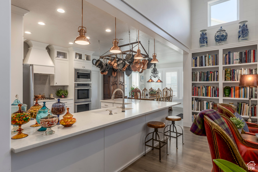Kitchen with a sink, appliances with stainless steel finishes, recessed lighting, wood finished floors, and a kitchen breakfast bar