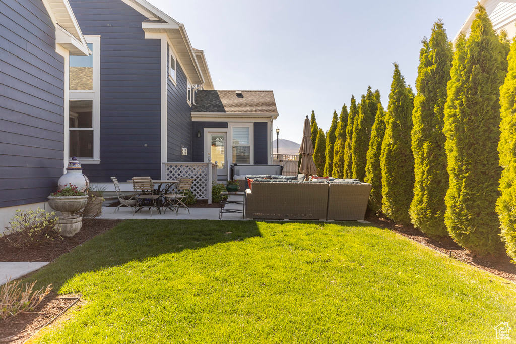 View of green lawn with an outdoor hangout area and a patio area