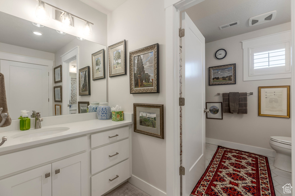 Bathroom featuring baseboards, vanity, and toilet