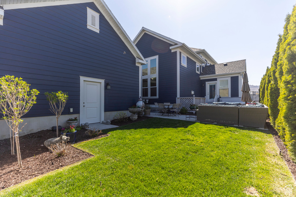 Rear view of property with a patio area, an outdoor hangout area, and a lawn