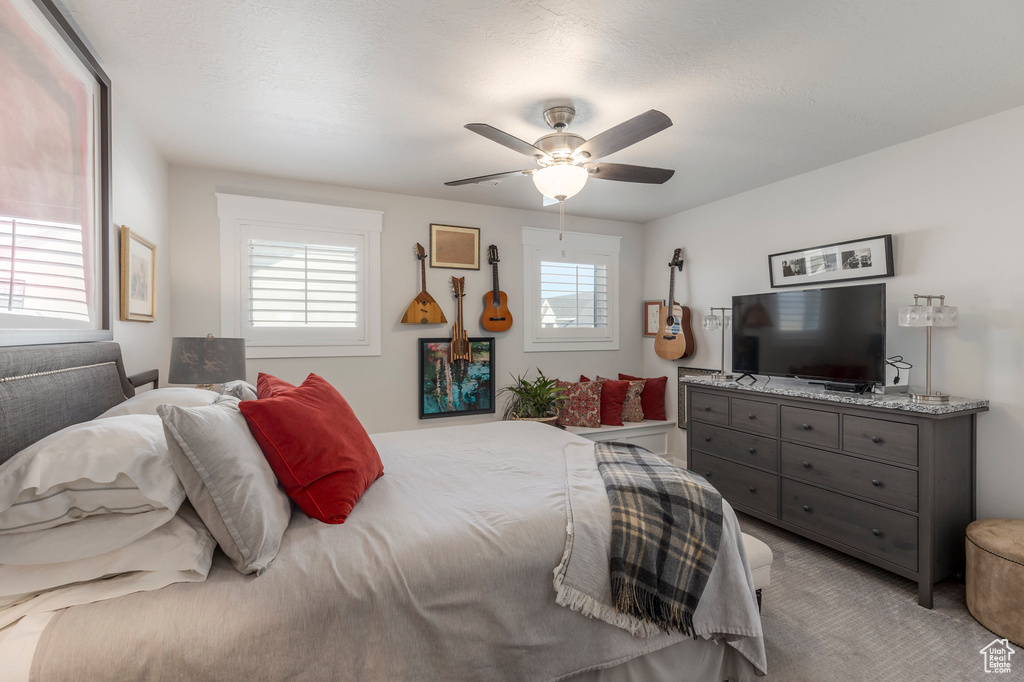 Bedroom featuring multiple windows, light carpet, and ceiling fan