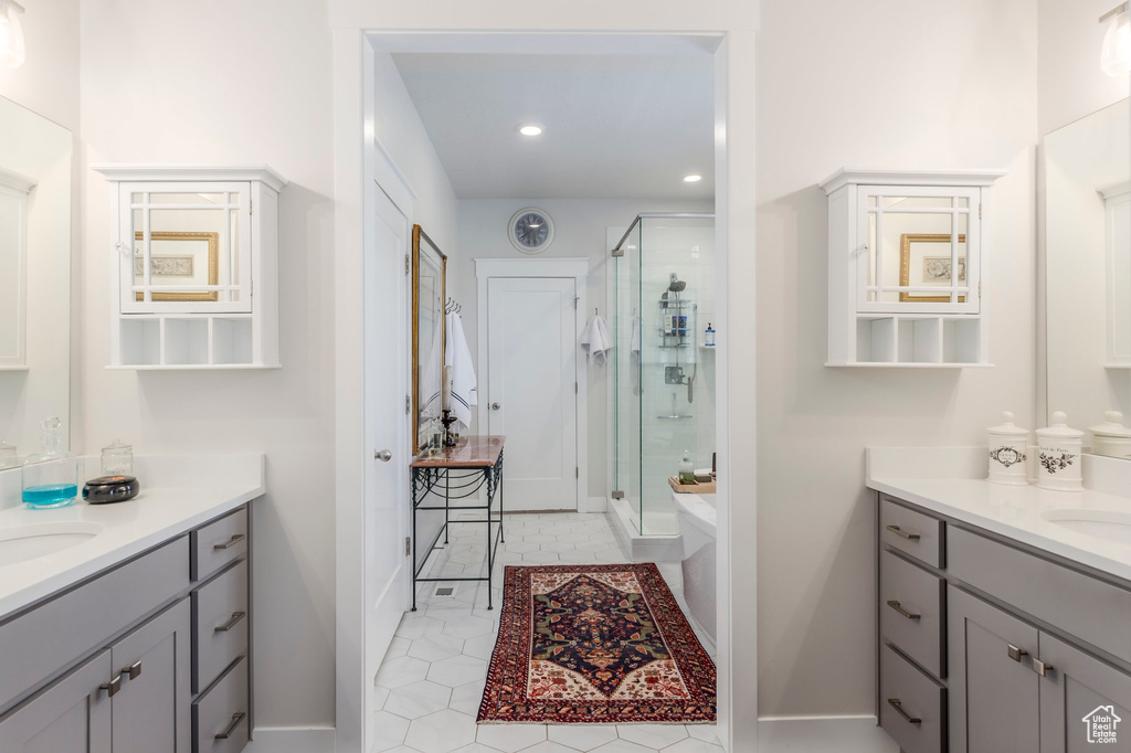 Full bath featuring a shower stall, two vanities, tile patterned floors, recessed lighting, and baseboards