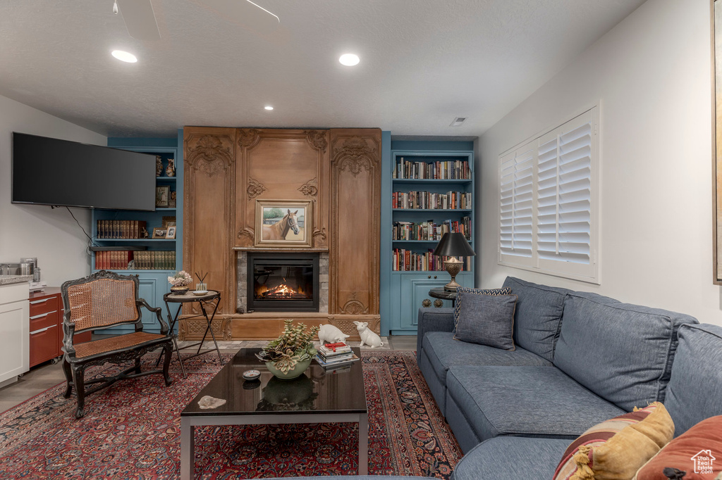 Living room featuring a large fireplace, wood finished floors, recessed lighting, and built in shelves