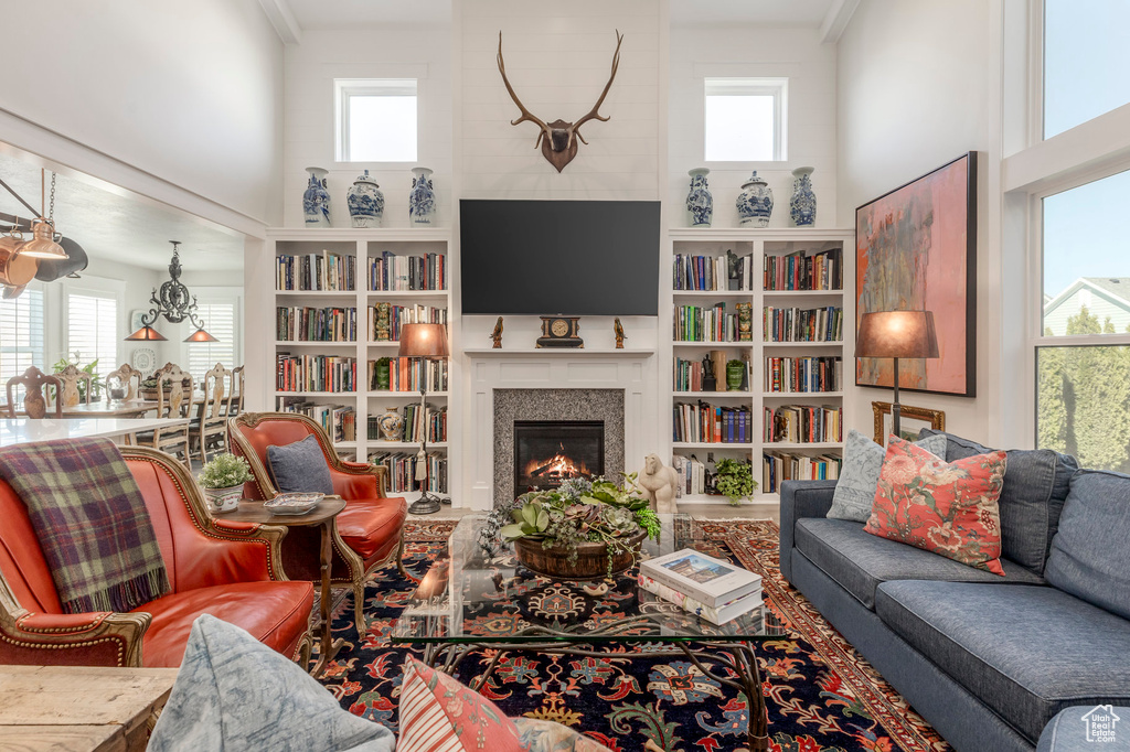 Living area with a high ceiling, a glass covered fireplace, and built in shelves