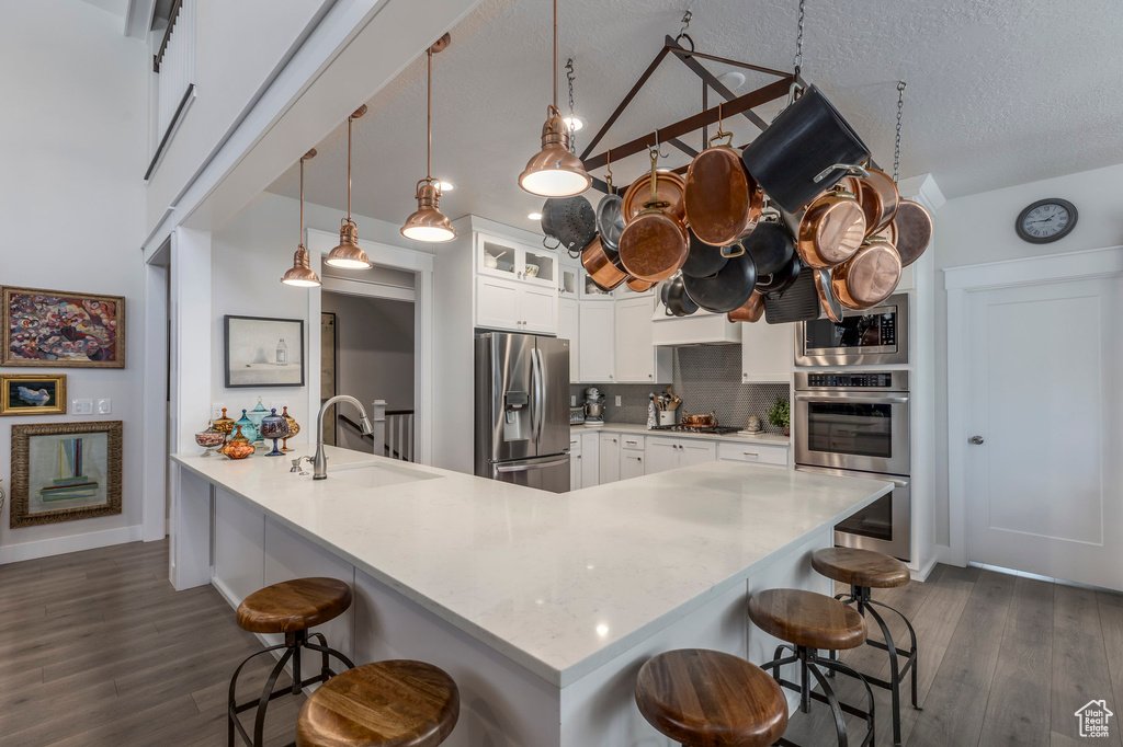 Kitchen featuring stainless steel appliances, a sink, a breakfast bar area, dark wood-type flooring, and a textured ceiling