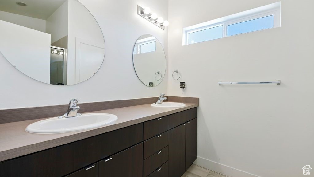Bathroom with double vanity, baseboards, and an enclosed shower