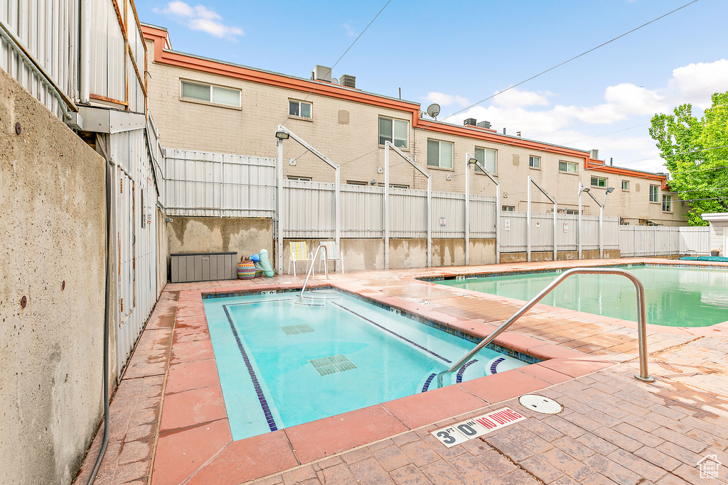 Community pool featuring fence and a jacuzzi