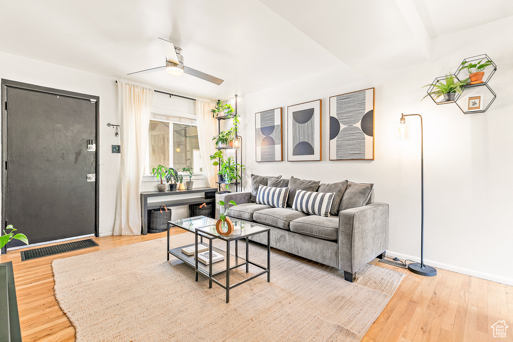 Living area featuring a ceiling fan, hardwood / wood-style flooring, and baseboards