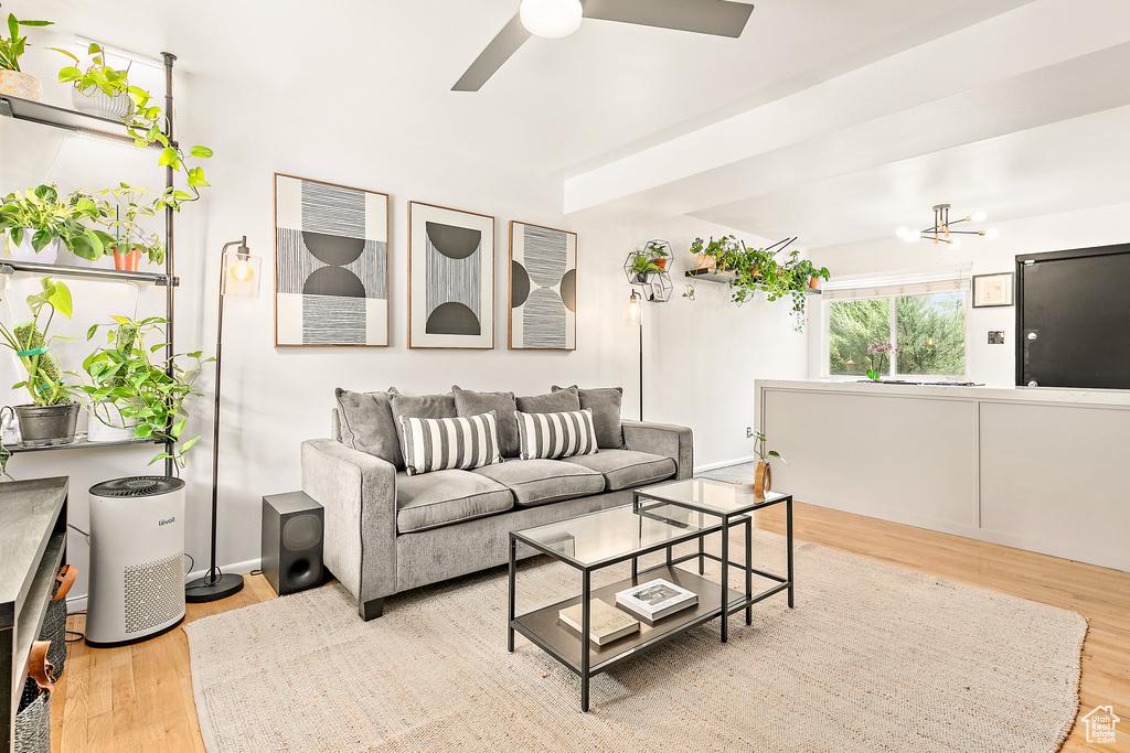 Living room with wood finished floors, ceiling fan, and a chandelier