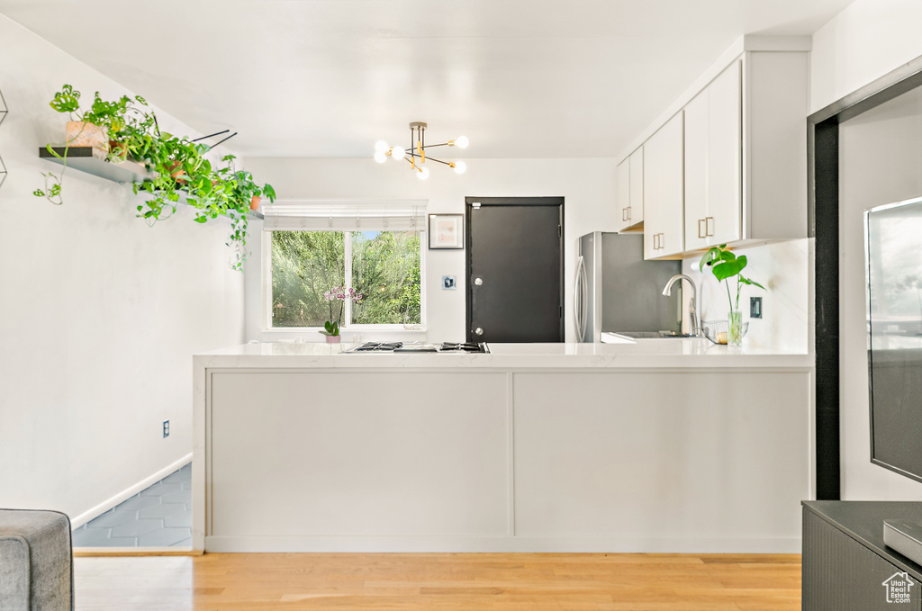 Kitchen featuring a chandelier, light wood-style floors, white gas cooktop, and light countertops