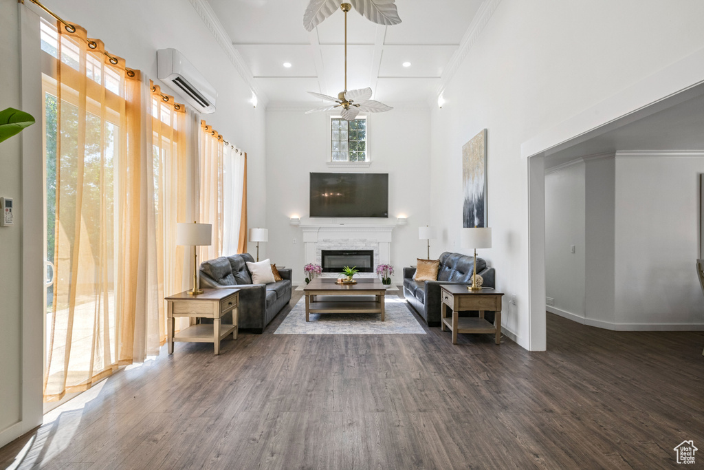 Living room featuring crown molding, a wall mounted air conditioner, a glass covered fireplace, and wood finished floors