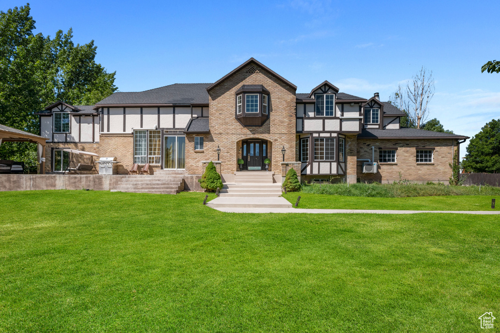 View of front of house featuring roof with shingles, a front yard, and brick siding