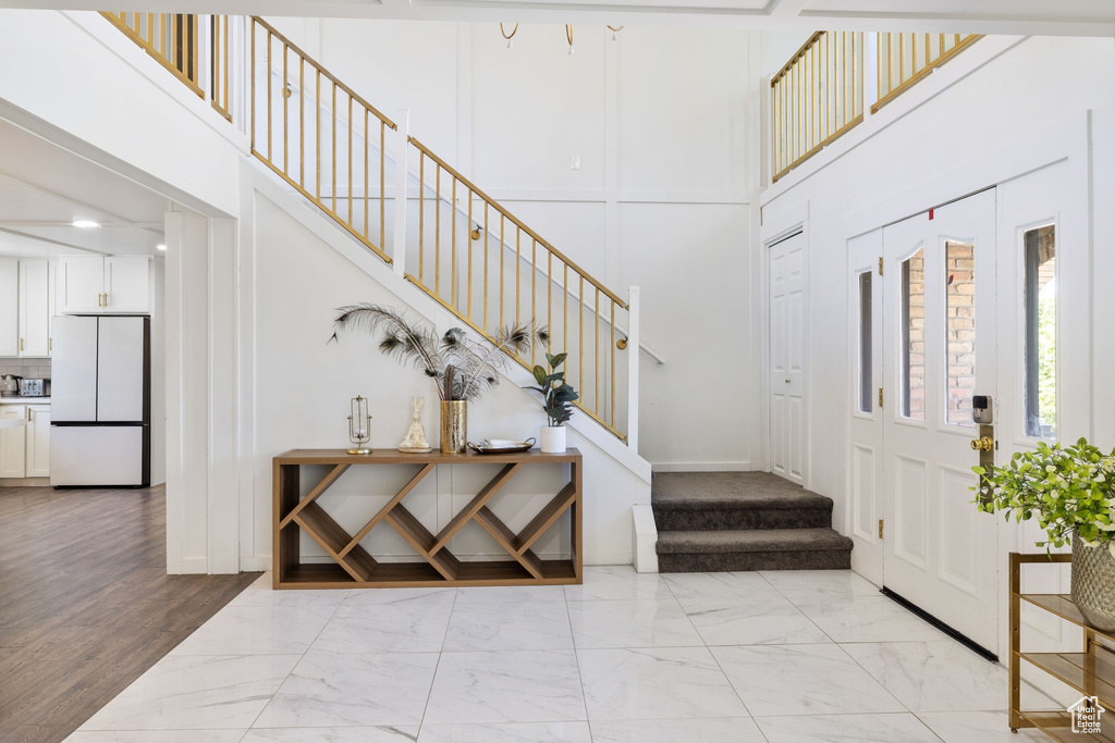 Entryway with light marble finish floors, stairway, and a high ceiling