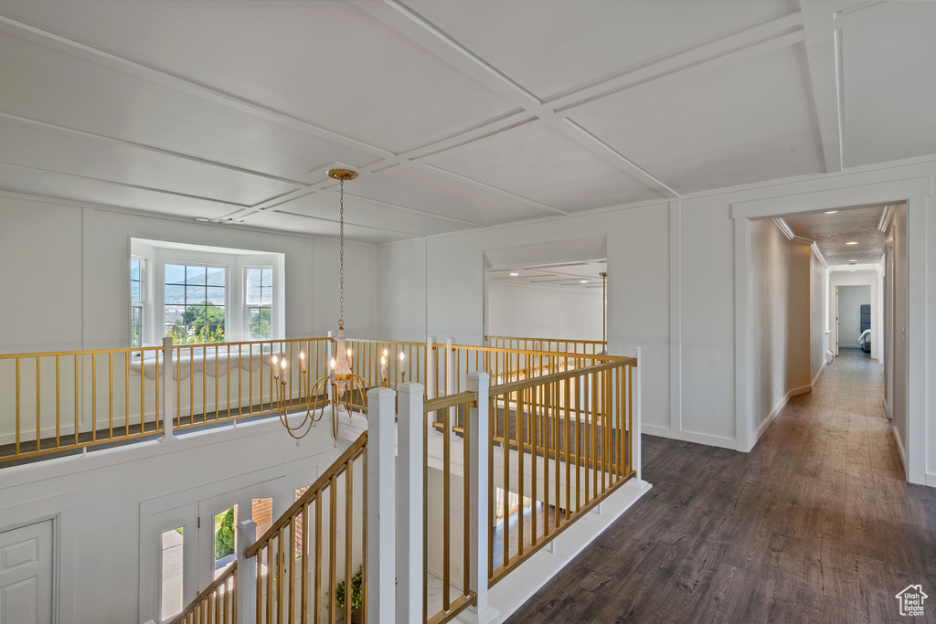 Hallway featuring coffered ceiling, wood finished floors, baseboards, an upstairs landing, and a decorative wall