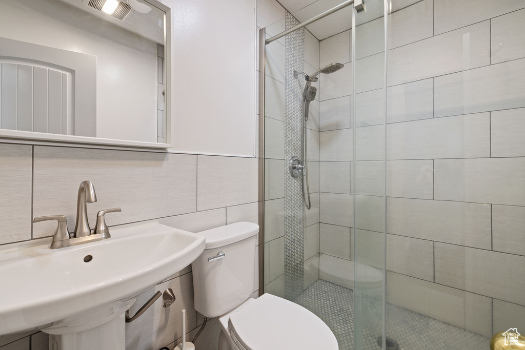 Full bathroom with a sink, tile walls, toilet, and a stall shower