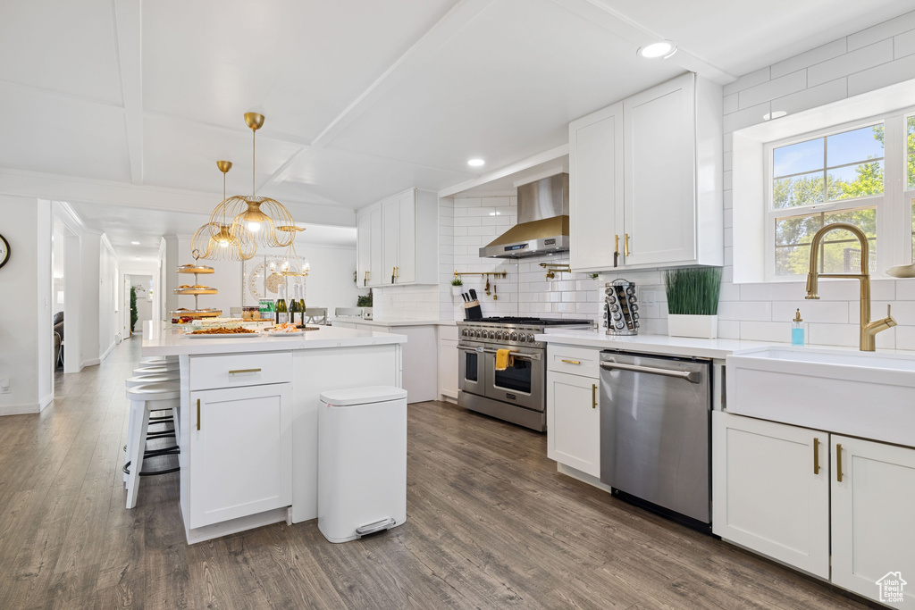 Kitchen featuring stainless steel appliances, wall chimney exhaust hood, decorative backsplash, white cabinetry, and recessed lighting