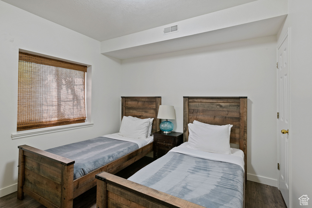 Bedroom with baseboards, visible vents, and wood finished floors