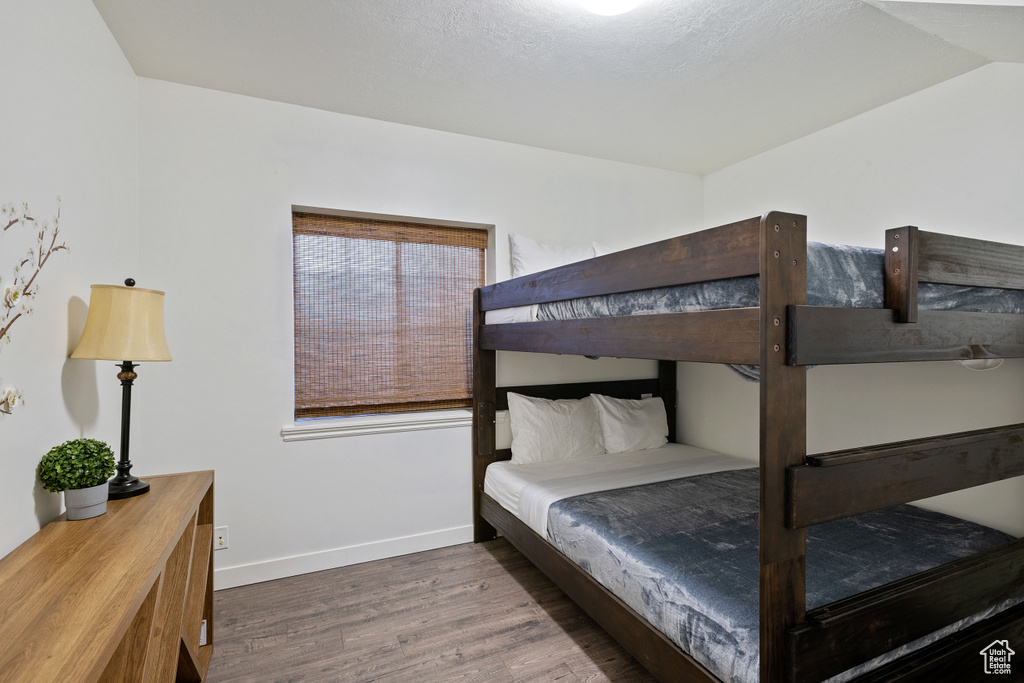 Bedroom with baseboards, wood finished floors, and lofted ceiling