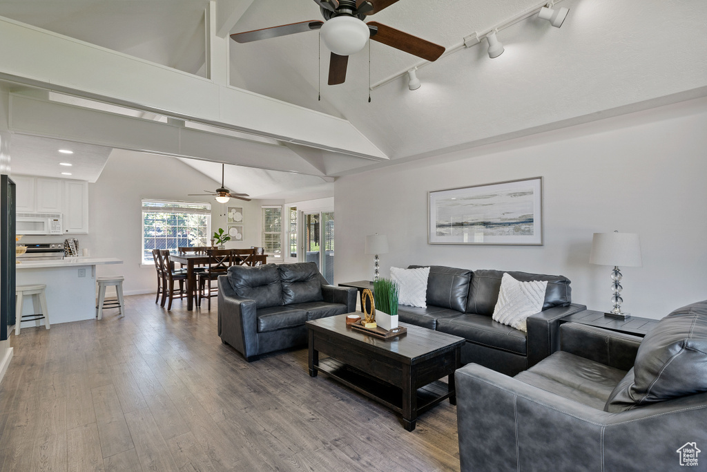 Living area with wood finished floors, baseboards, high vaulted ceiling, rail lighting, and a ceiling fan