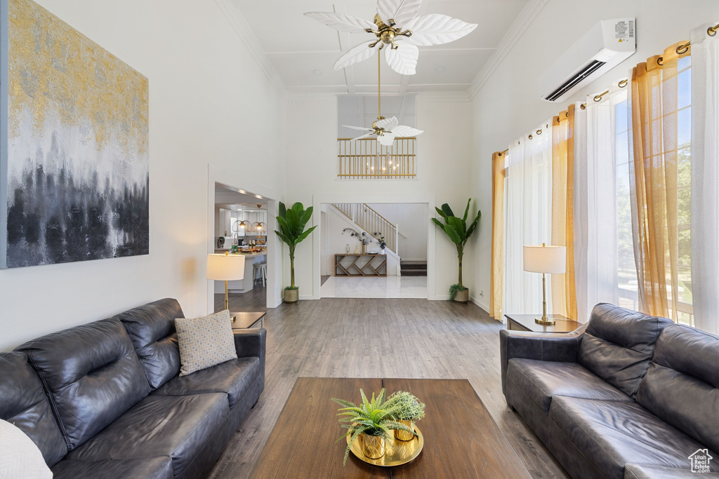 Living room featuring a wall mounted AC, stairway, ornamental molding, wood finished floors, and ceiling fan