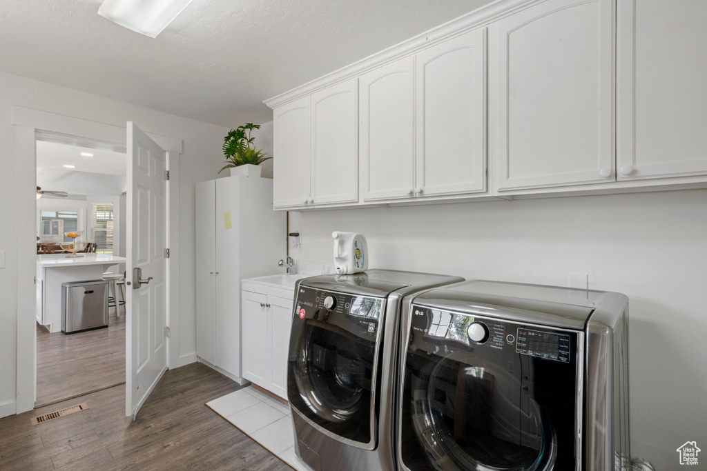 Laundry area with washer and clothes dryer, visible vents, dark wood finished floors, cabinet space, and a wealth of natural light