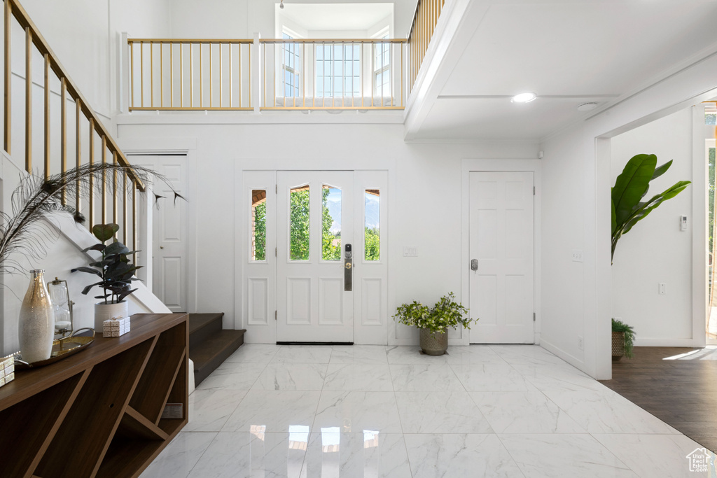 Foyer entrance with baseboards, stairs, a high ceiling, and a wealth of natural light