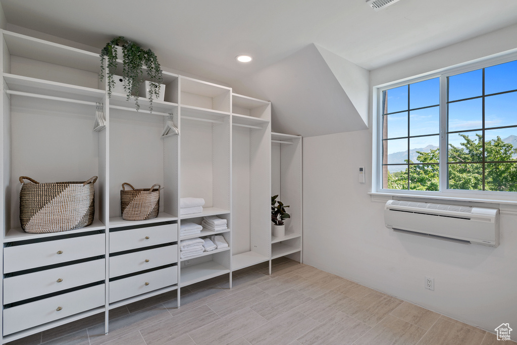 Walk in closet with visible vents, a wall mounted AC, and wood finished floors