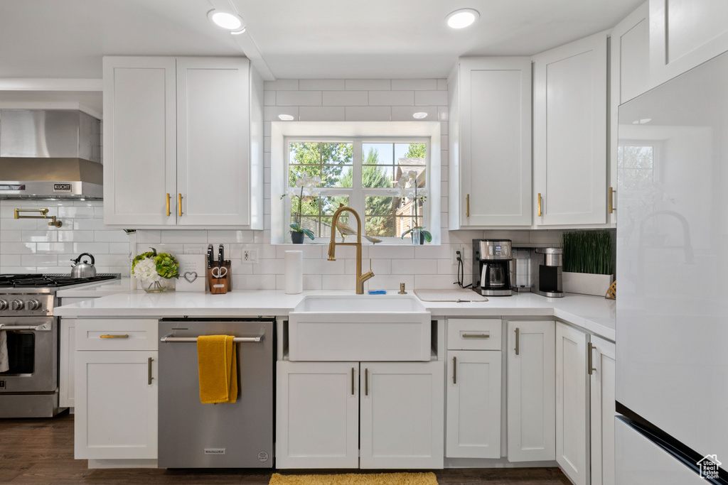 Kitchen with a sink, wall chimney exhaust hood, backsplash, and stainless steel appliances