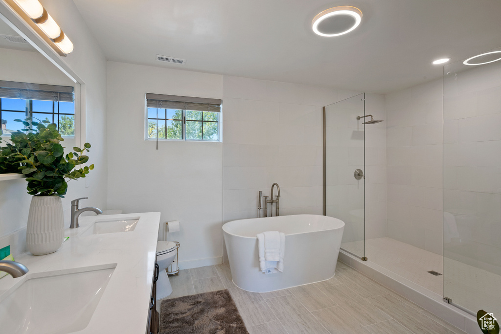 Full bathroom with visible vents, a sink, a freestanding tub, and tiled shower