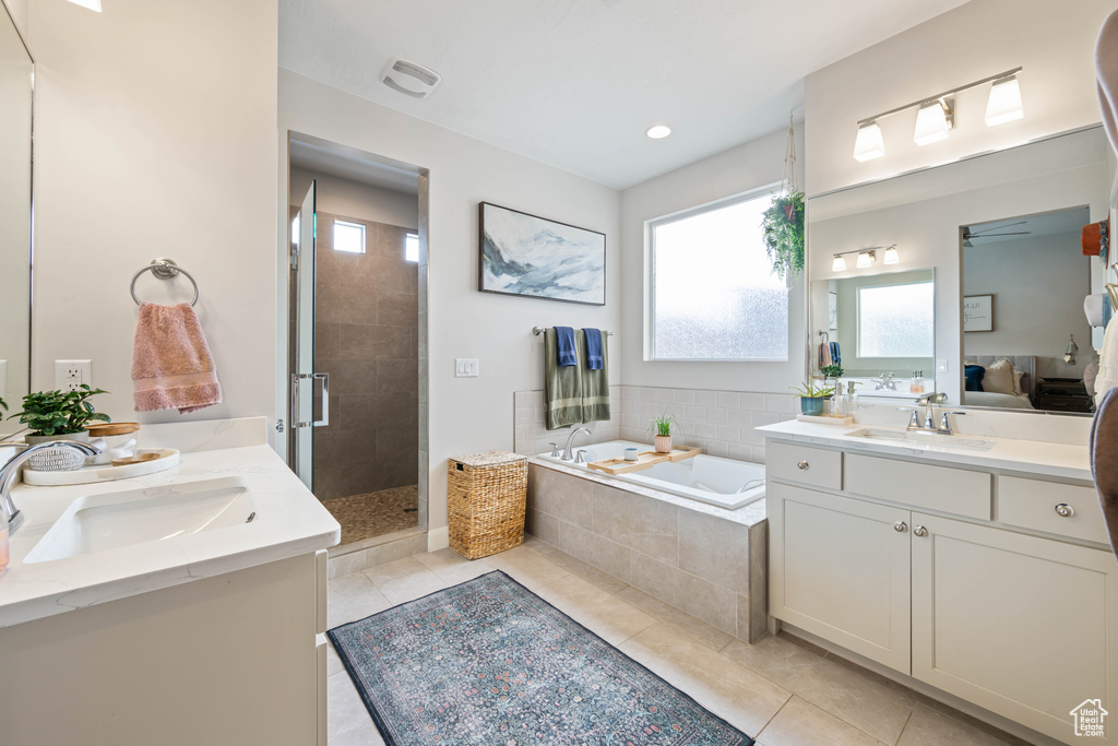 Full bathroom with tile patterned floors, two vanities, a shower stall, and a garden tub