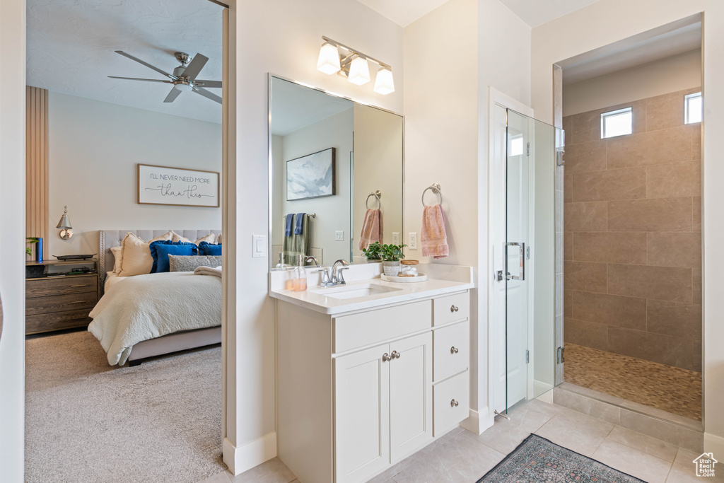 Ensuite bathroom featuring a ceiling fan, a tile shower, and vanity