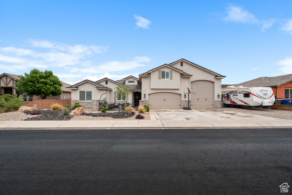Traditional home with stucco siding, stone siding, concrete driveway, and fence
