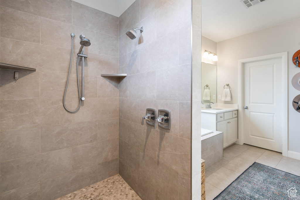 Bathroom featuring tiled shower, vanity, and tile patterned flooring