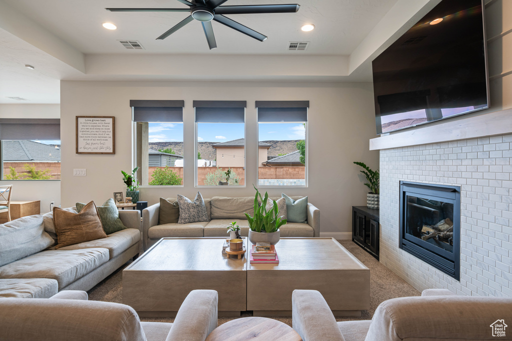 Carpeted living room featuring a ceiling fan, a fireplace, and recessed lighting
