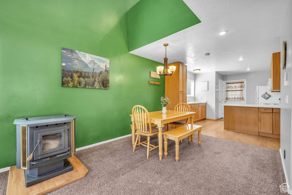 Dining area featuring a wood stove, a chandelier, baseboards, recessed lighting, and light wood-style flooring