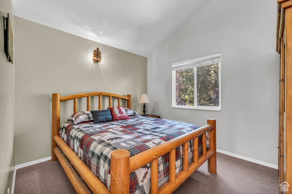 Carpeted bedroom featuring vaulted ceiling and baseboards